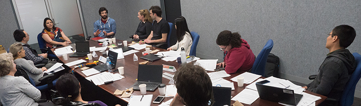 A group of people sitting at a table with a computer
